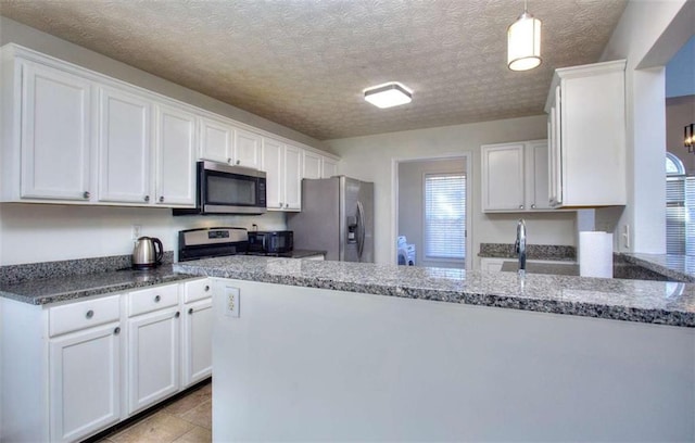 kitchen with dark stone counters, decorative light fixtures, a textured ceiling, white cabinets, and appliances with stainless steel finishes