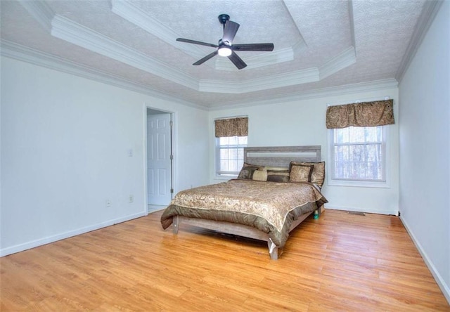 bedroom featuring a raised ceiling, crown molding, hardwood / wood-style flooring, ceiling fan, and a textured ceiling