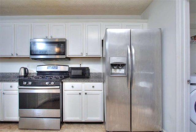 kitchen featuring white cabinets, dark stone counters, a textured ceiling, and appliances with stainless steel finishes