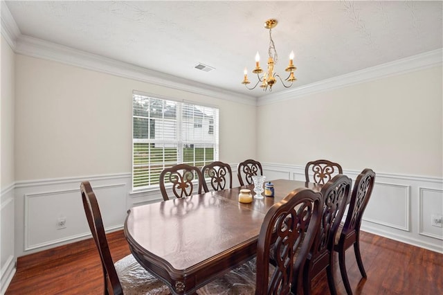 dining area featuring dark wood-type flooring, an inviting chandelier, and crown molding