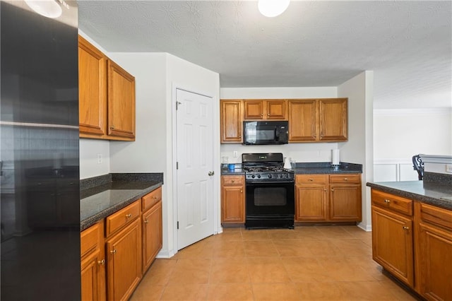 kitchen with light tile patterned floors, dark stone countertops, and black appliances