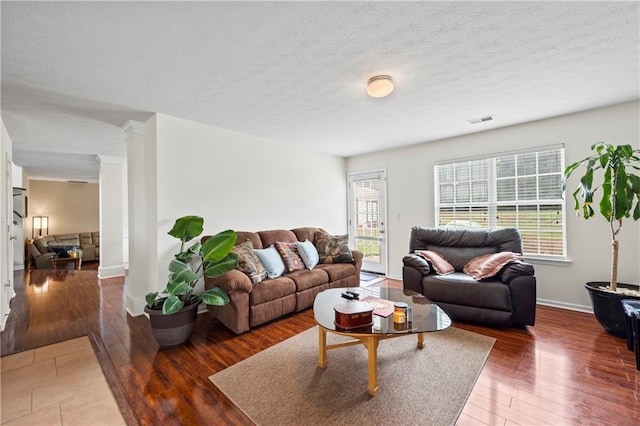 living room with a textured ceiling, dark hardwood / wood-style flooring, and a healthy amount of sunlight