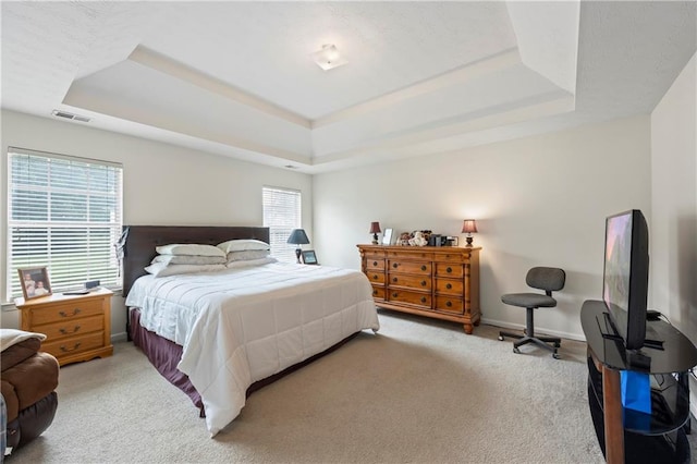 bedroom featuring a tray ceiling and light colored carpet