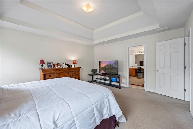 bedroom with carpet floors, a raised ceiling, and ensuite bath