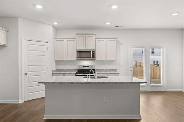 kitchen with white cabinets, sink, stainless steel appliances, and an island with sink