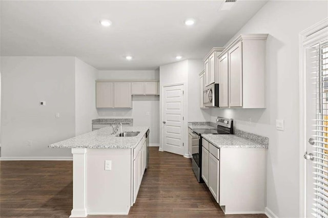 kitchen with a center island with sink, sink, light stone counters, dark hardwood / wood-style flooring, and stainless steel appliances