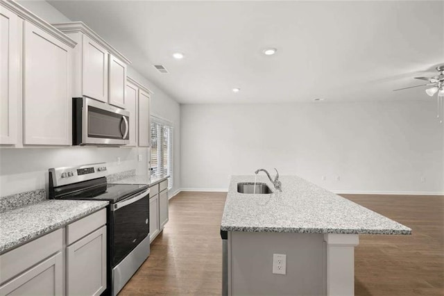 kitchen with dark hardwood / wood-style flooring, sink, appliances with stainless steel finishes, and an island with sink