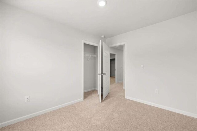 unfurnished bedroom featuring light carpet and a closet