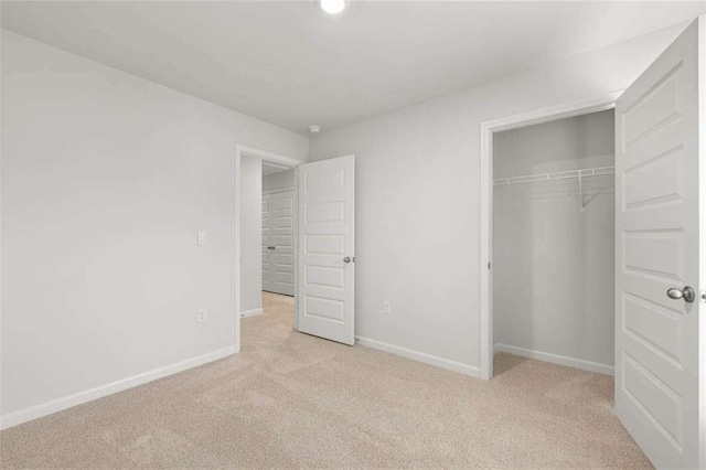 unfurnished bedroom featuring light carpet and a closet