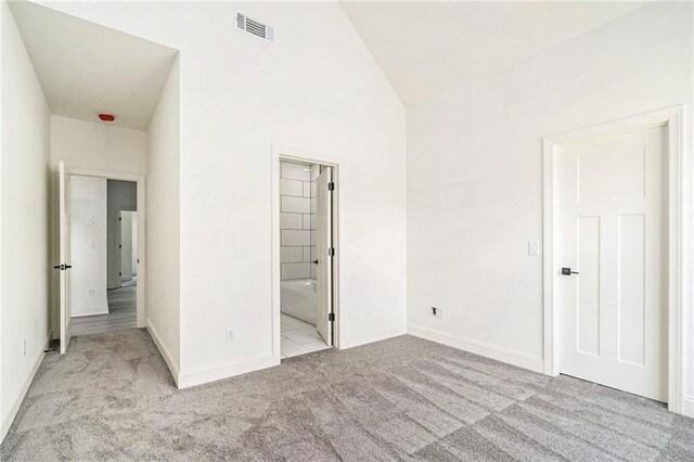 unfurnished bedroom featuring connected bathroom and light colored carpet