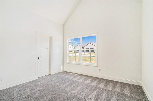 carpeted empty room featuring high vaulted ceiling