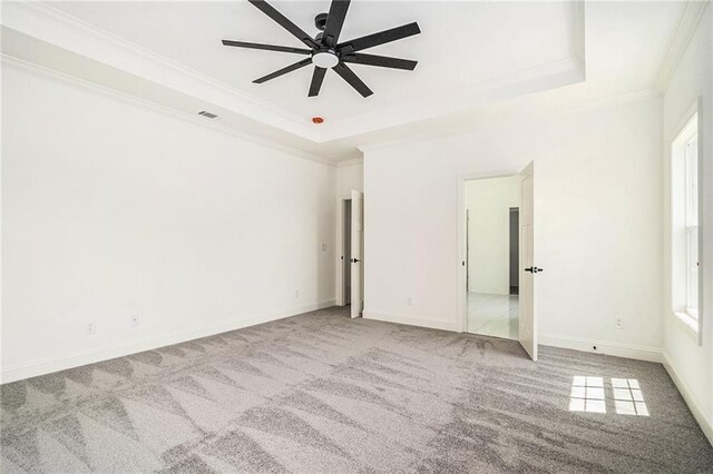 unfurnished bedroom featuring a tray ceiling, ceiling fan, carpet, and ornamental molding