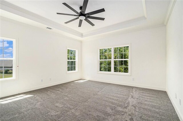 carpeted empty room featuring ceiling fan, ornamental molding, and a tray ceiling