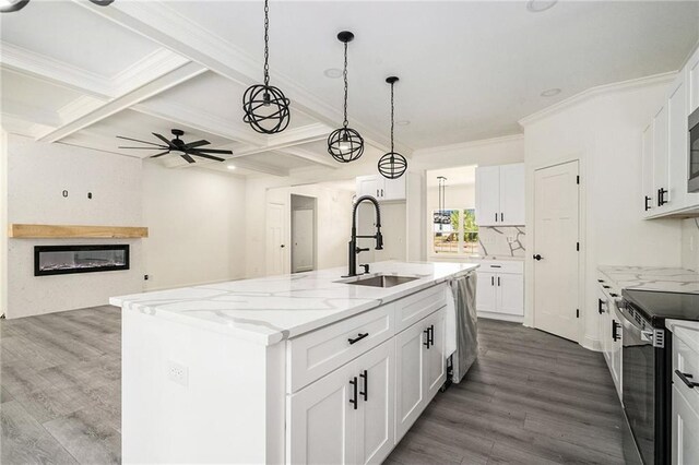 kitchen with white cabinets, sink, an island with sink, light stone counters, and stainless steel appliances