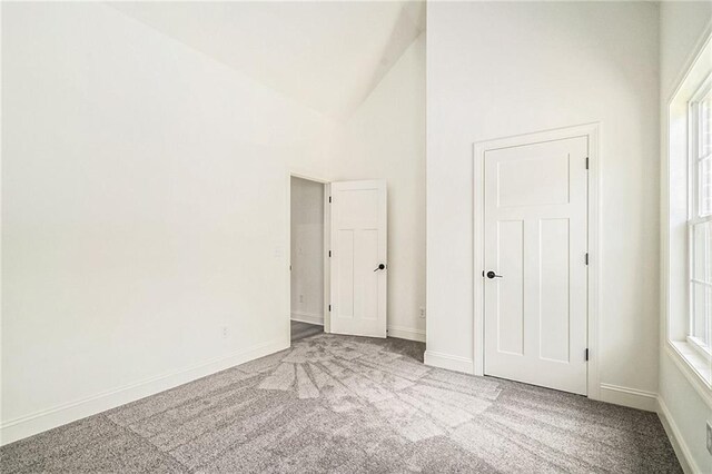 interior space with high vaulted ceiling and light colored carpet