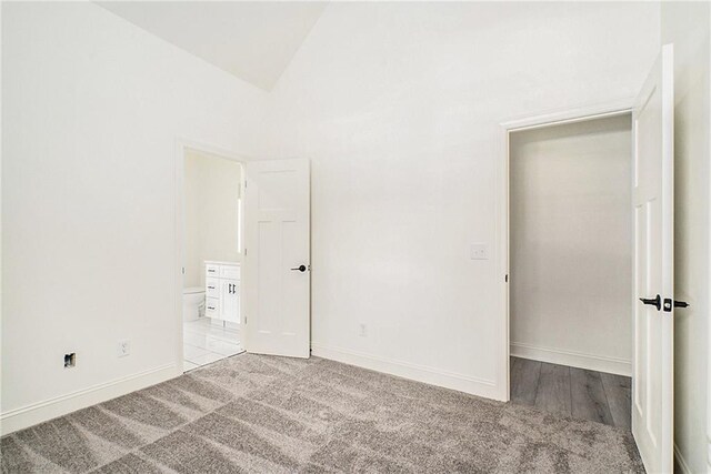 unfurnished bedroom featuring light carpet and vaulted ceiling