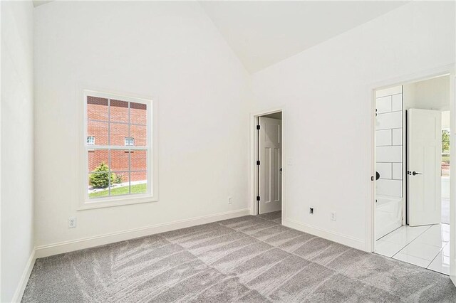 carpeted spare room featuring high vaulted ceiling