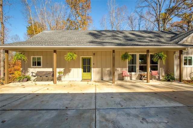 back of house featuring board and batten siding, a shingled roof, and a patio