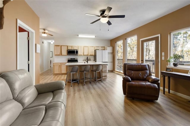 living room featuring ceiling fan, sink, and light hardwood / wood-style flooring