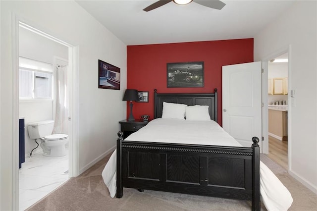 bedroom with light carpet, ensuite bathroom, and ceiling fan