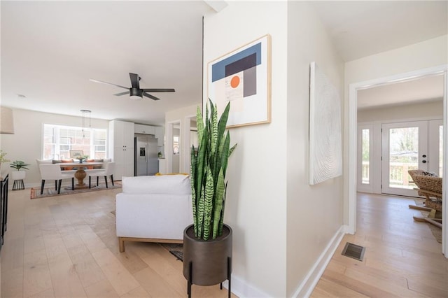hallway with light wood-style floors, baseboards, and a wealth of natural light