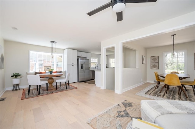 living area featuring baseboards, light wood-style floors, visible vents, and ceiling fan