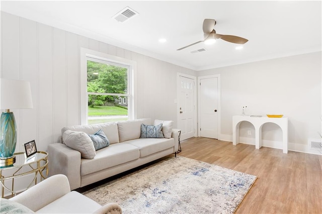 living room featuring baseboards, a ceiling fan, light wood-type flooring, and visible vents