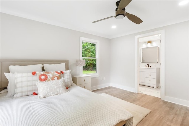 bedroom featuring a ceiling fan, a sink, baseboards, light wood-style floors, and ensuite bathroom