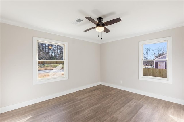 spare room featuring visible vents, baseboards, ceiling fan, and wood finished floors
