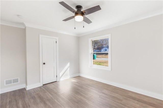 unfurnished room featuring visible vents, ornamental molding, a ceiling fan, and wood finished floors