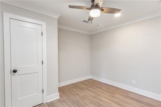 empty room with visible vents, crown molding, baseboards, a ceiling fan, and light wood finished floors