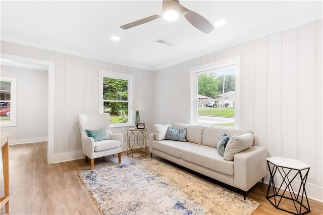 living room with a wealth of natural light, a ceiling fan, light wood-type flooring, and visible vents