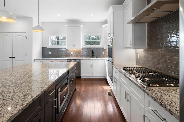 kitchen featuring white cabinetry, stainless steel appliances, wall chimney exhaust hood, and dark wood-style flooring