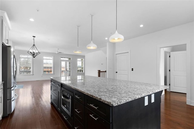 kitchen with white cabinets, dark wood-style flooring, appliances with stainless steel finishes, and a kitchen island