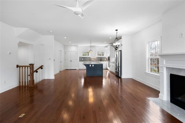 unfurnished living room with recessed lighting, a premium fireplace, baseboards, and dark wood-style flooring