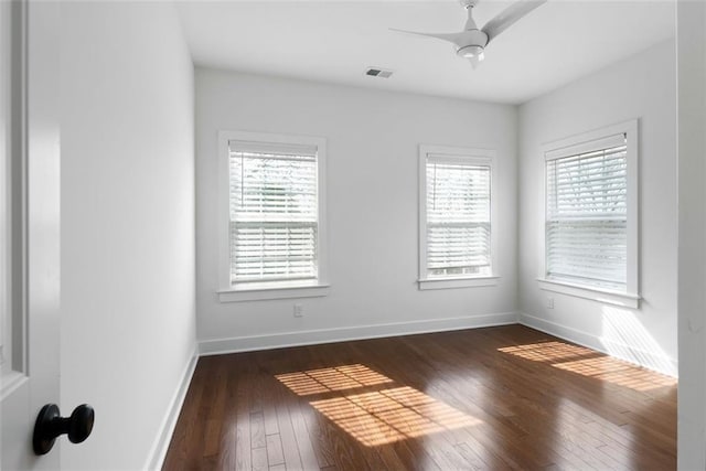 unfurnished room featuring dark wood finished floors, baseboards, visible vents, and a wealth of natural light