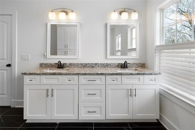 full bath with double vanity, baseboards, and a sink