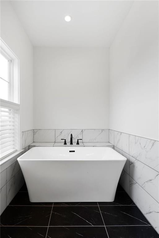 bathroom featuring a freestanding tub, marble finish floor, and wainscoting