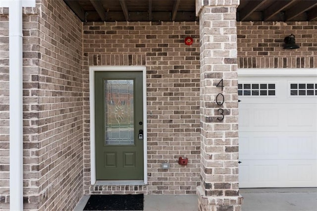 doorway to property featuring brick siding and a garage