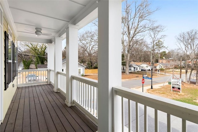 wooden terrace with a porch, a ceiling fan, and a residential view