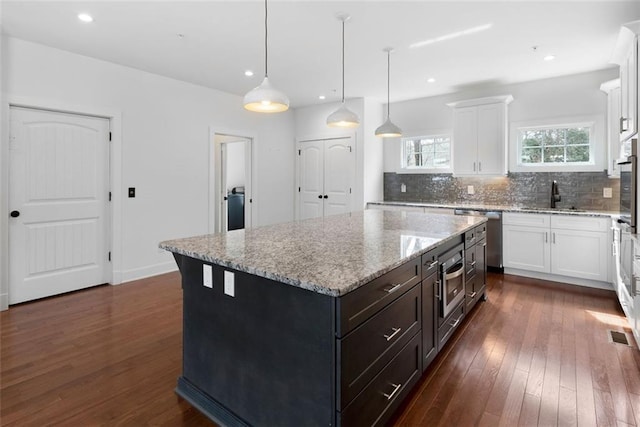 kitchen with a sink, dark wood-style floors, appliances with stainless steel finishes, and white cabinets