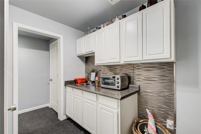 1360 Stampmill Way, Lawrenceville, GA 30043 - kitchen with backsplash, a sink, dark colored carpet, white cabinetry, and dark countertops