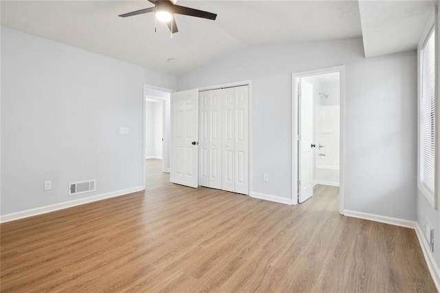 unfurnished bedroom featuring ensuite bathroom, ceiling fan, vaulted ceiling, and light hardwood / wood-style flooring