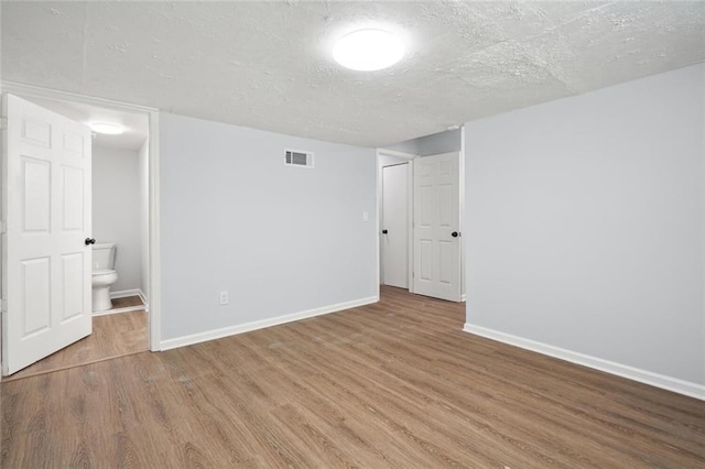 unfurnished room featuring wood-type flooring and a textured ceiling