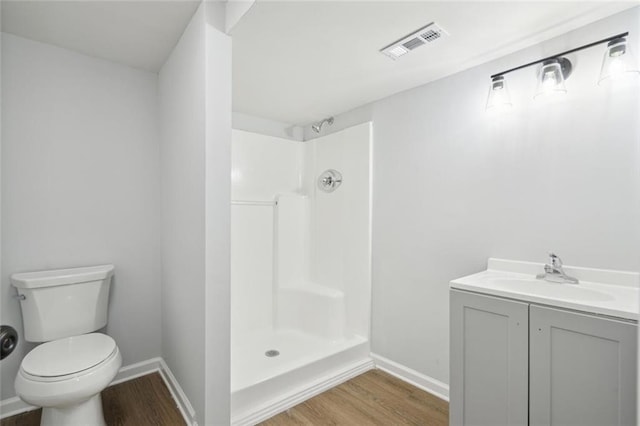 bathroom with hardwood / wood-style floors, vanity, toilet, and a shower