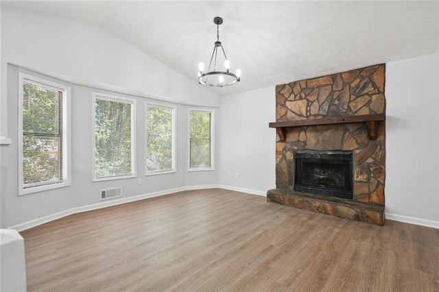 unfurnished living room featuring lofted ceiling, a fireplace, a wealth of natural light, and a chandelier