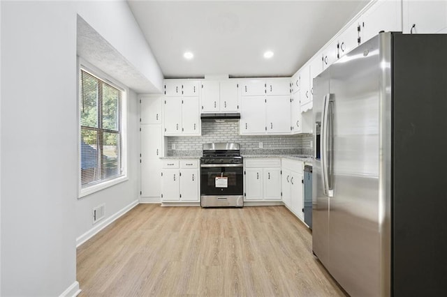 kitchen with white cabinets, appliances with stainless steel finishes, backsplash, and light hardwood / wood-style floors