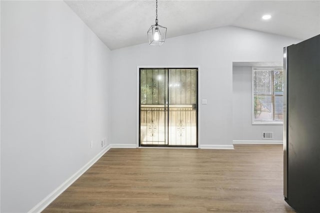 empty room with hardwood / wood-style floors and lofted ceiling