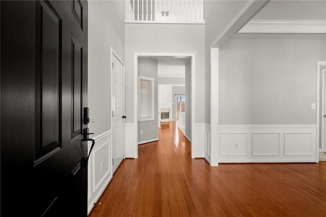 foyer featuring a wainscoted wall, wood finished floors, and ornamental molding