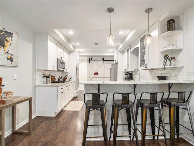 kitchen featuring white cabinets, kitchen peninsula, dark wood-type flooring, and appliances with stainless steel finishes